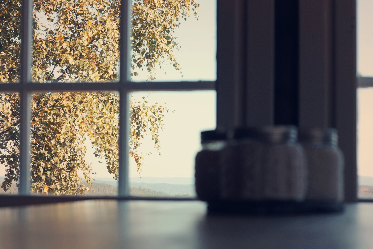 Glass jars on a windowsill at a homestead in warm autumn light